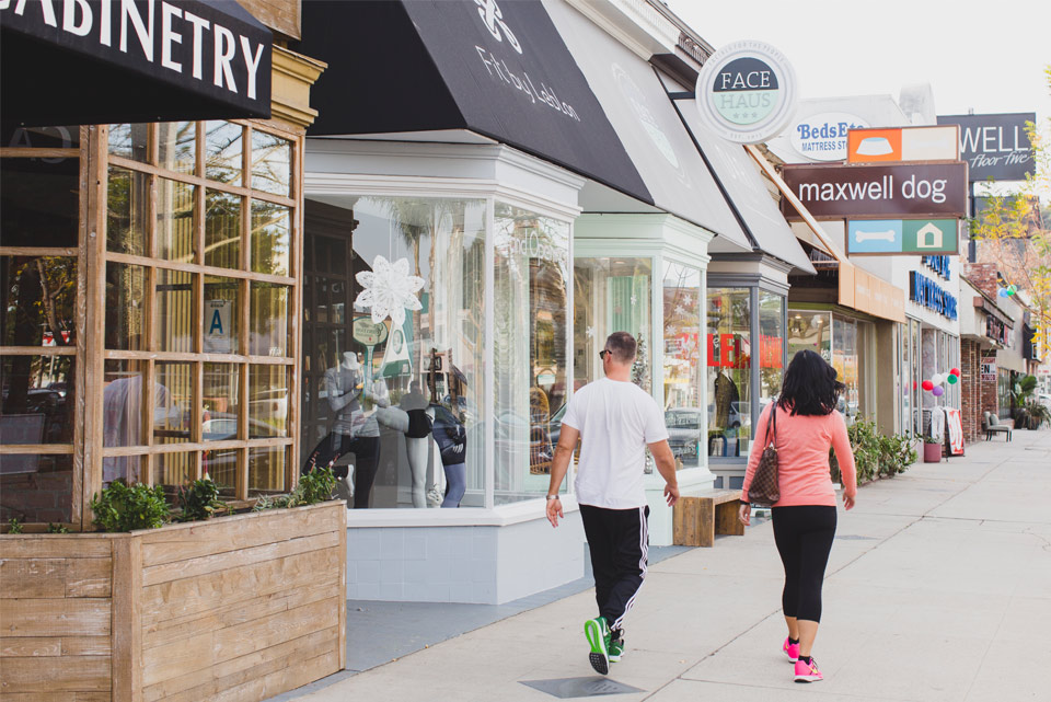 Two people walking past boutique storefronts