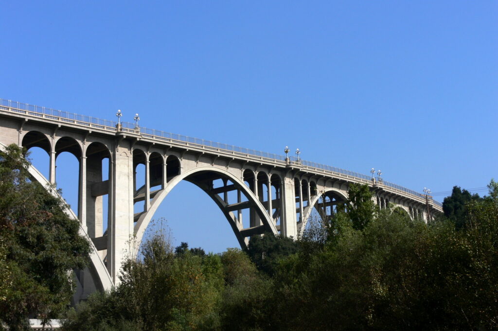 Concrete arched bridge over green treetops
